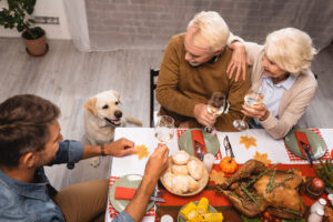 high-angle-view-of-golden-retriever-near-family-holding-glasses-of-white-wine-during-thanksgiving-dinner