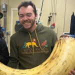 Male vet wearing a hakuna matata sweatshirt holding a giant prop